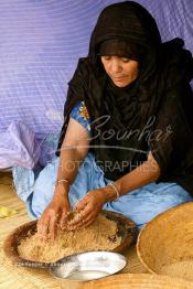 Image du Maroc Professionnelle de  Sous une tente bédouine une femme du Sahara  prépare le couscous durant le grand Moussem de Tan Tan, classé en 2005 patrimoine immatériel humain mondial de l'Unesco. Le Moussem est une sorte de foire annuelle, à la fois économique, culturelle et sociale. Chaque année la majorité des tribus et des grandes familles nomades du désert se retrouvent sur un site désertique "Place de la Tolérance et de la Paix " à la périphérie de Tan Tan où  danse, chants, course de chameaux et fantasia font partie des festivités. , Samedi 18 septembre 2004, ((Photo / Abdeljalil Bounhar)